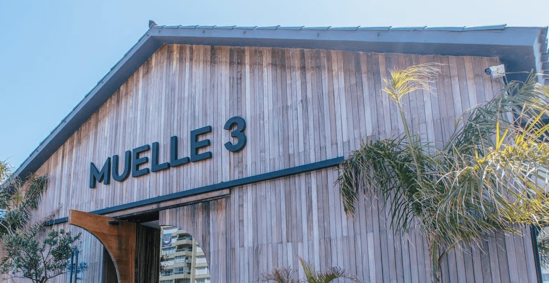 Fachada de madera de Muelle 3 con el nombre del restaurante, de día