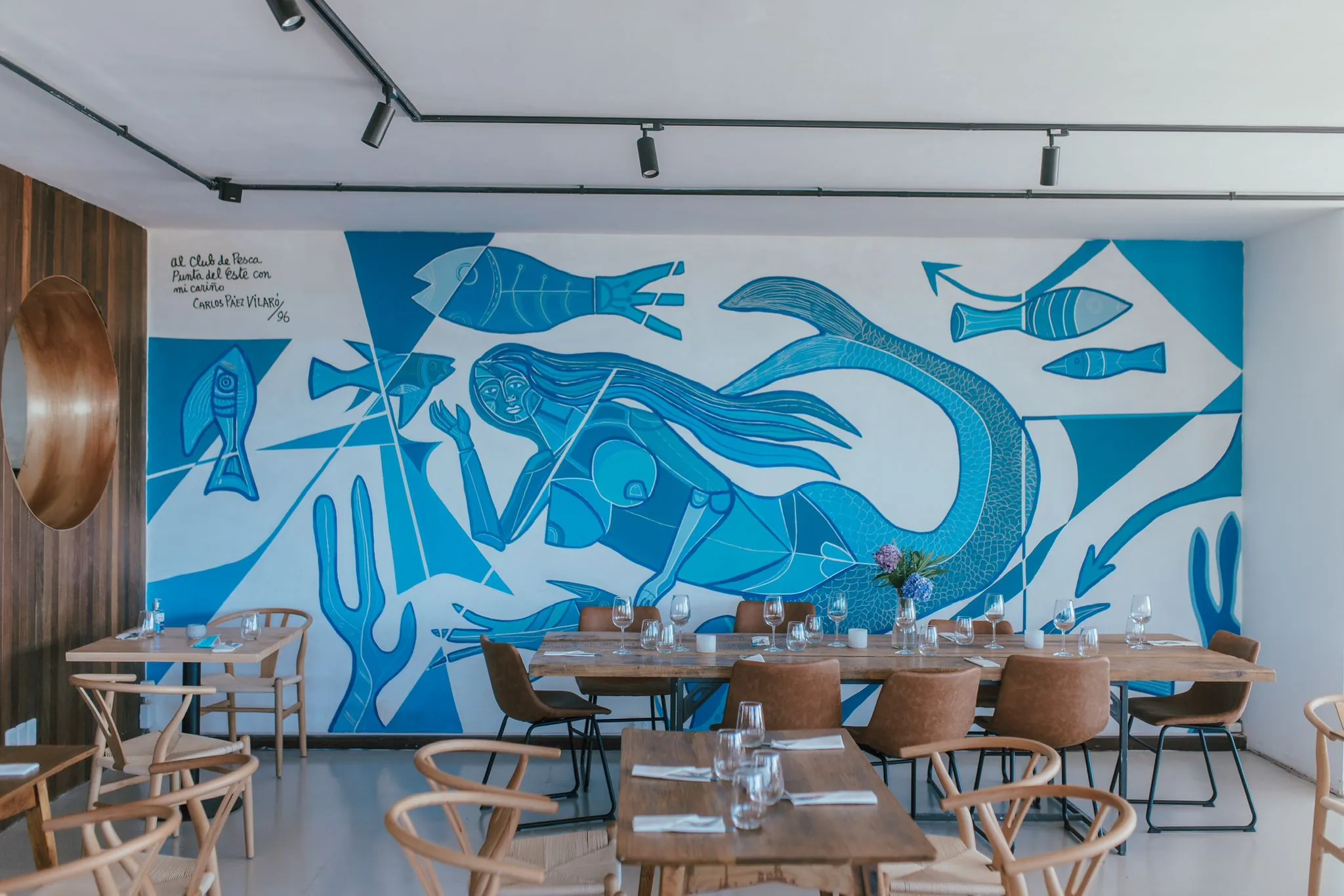 Salón de Muelle 3 con el mural de Páez Vilaró y mesas puestas, con luz natural